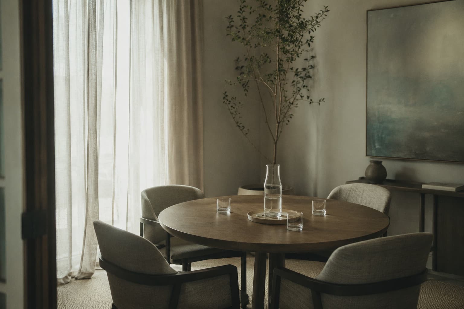 An empty client meeting room — round table, four chairs, water carafe and glasses set out